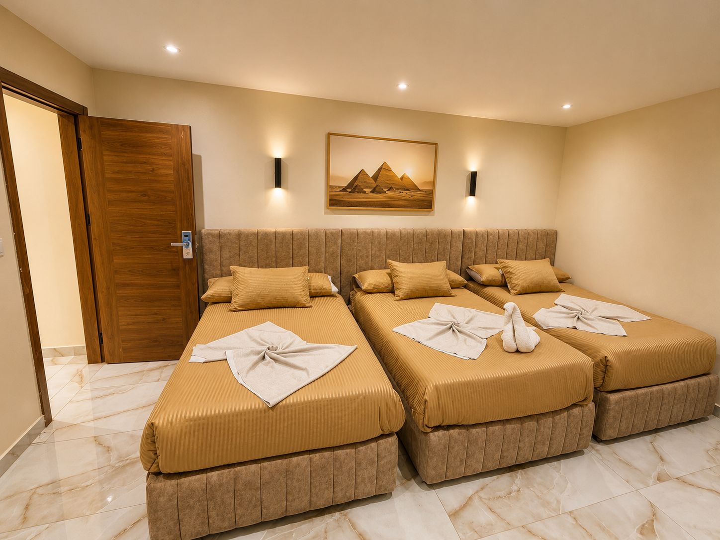A hotel room with two beds, a wooden door, a wall-mounted painting, and a marble floor.