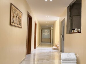 A hotel corridor with a framed ancient Egyptian artwork, a reception desk, and a bathroom with toiletries. - Amon Ra Hotel (Giza)