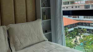 Een hotelkamer met een bed, een airconditioning en uitzicht op de omliggende gebouwen.