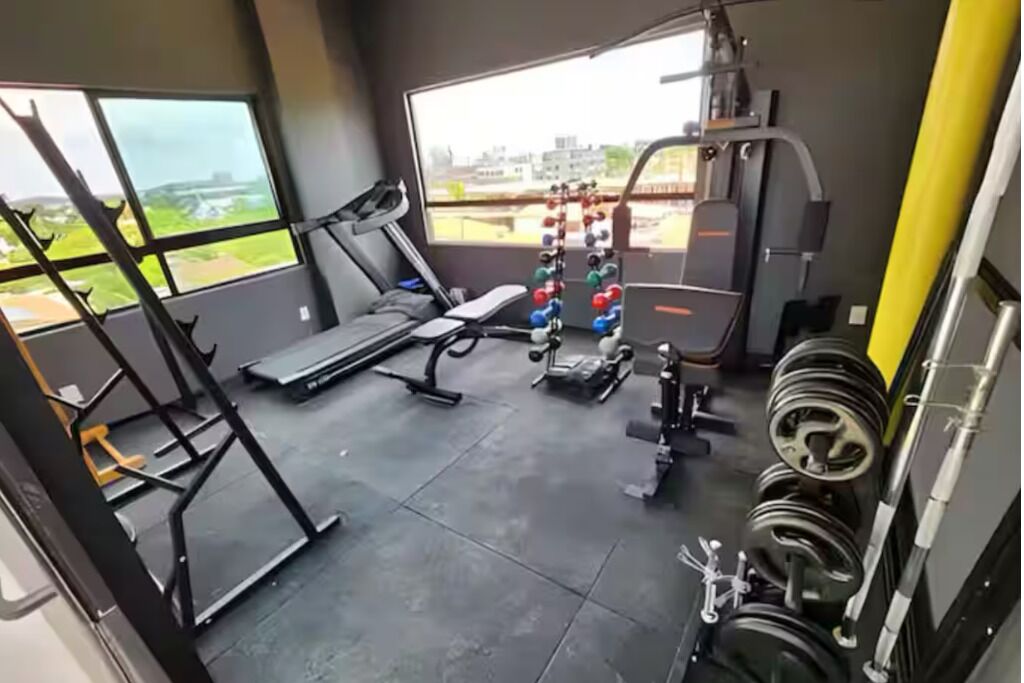 A gym with a treadmill, weight bench, and various exercise equipment.