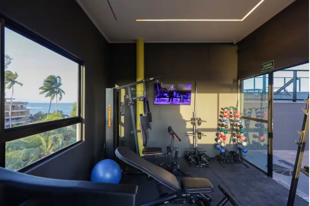 A gym with exercise equipment, a bench, and a wall-mounted TV.