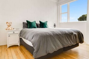Un dormitorio con cama, mesita de noche y ventana.