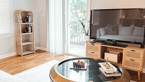 Ein Wohnzimmer mit einem runden Glastisch, einer Couch, einem Fernseher und einem Bücherregal.