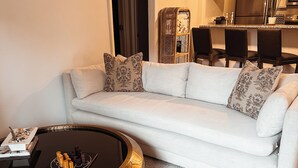 Ein modernes Wohnzimmer mit einem weißen Sofa, einem runden Couchtisch und einem Essbereich im Hintergrund.