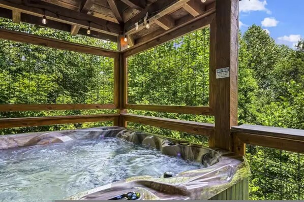 Un espace avec un bain à remous, doté de rampes en bois et offrant une vue sur un feuillage verdoyant et luxuriant.