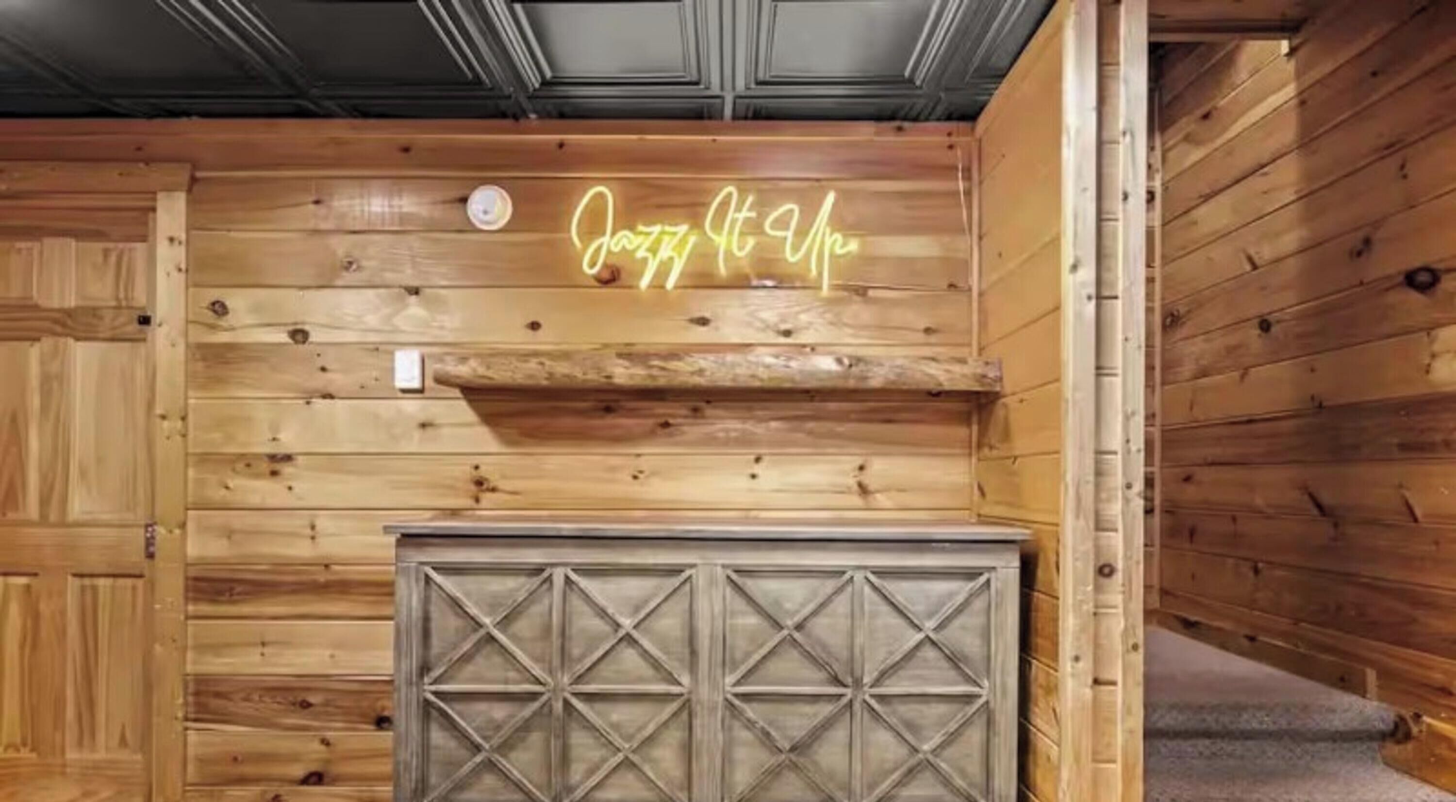 Un interior de madera con un letrero de neón que dice 'Jazz It Up' y un panel decorativo de metal.