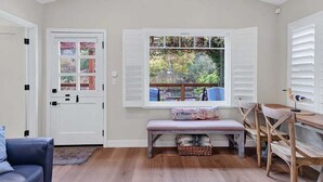 A room with a bench, a table, and a window with shutters. - Coastal Retreat in the Heart of Capitola Village - Steps from the Beach! (Capitola)