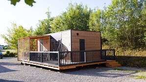A small, single-story cabin with a balcony, a fan, and a window. - Familienfreundliches Mobilehome im Vital Camp Bayerbach (Bayerbach)