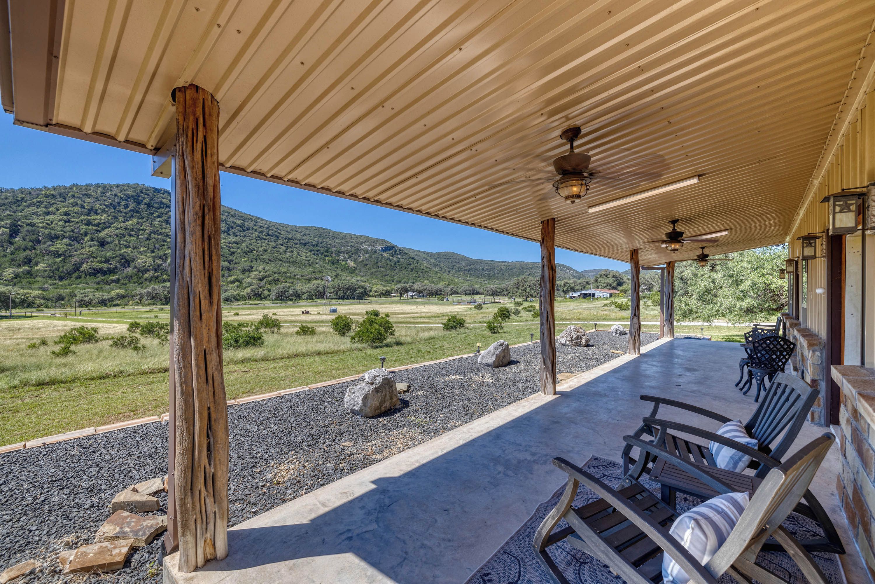 A covered outdoor seating area with a view of a hilly landscape.