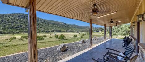 A covered outdoor seating area with a view of a hilly landscape.