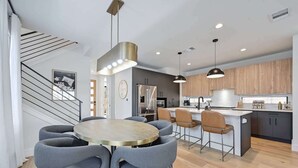Una cucina moderna con isola centrale, sedie rivestite di grigio e illuminazione a sospensione.