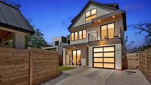 Una casa moderna a due piani con garage, balcone e ingresso ben illuminato.