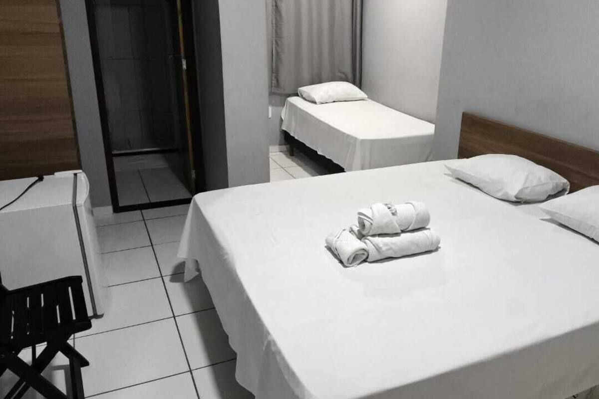 Una habitación de hotel con una cama grande, dos camas más pequeñas, un escritorio y una silla.