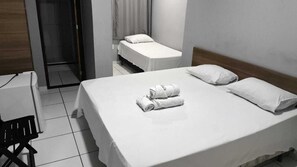 Una camera d'albergo con un letto grande, due letti singoli, una scrivania e una sedia.