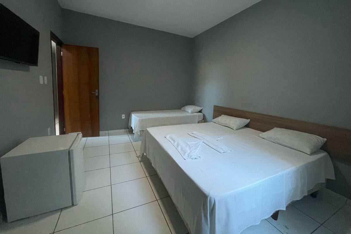 Habitación de hotel con dos camas, una zona de estar pequeña y un televisor en la pared.