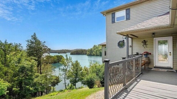 Ein Haus mit einer Holzterrasse mit Blick auf einen See, umgeben von Bäumen.