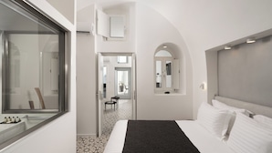 Une chambre d’hôtel moderne avec un grand lit, une fenêtre, une petite table et un miroir.
