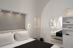 A modern bedroom with a bed, bedside tables, a mirror, and a wall-mounted shelf. - ORANA Residence Santorini (Thira - Santorini)