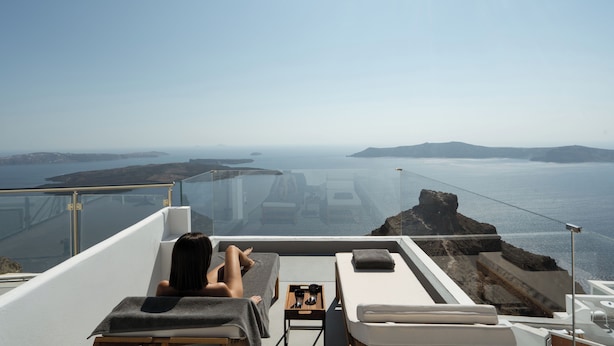 Une personne se détend sur un transat, avec vue sur la mer et les îles.