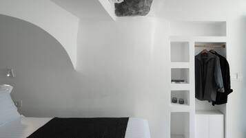 A modern bedroom with a bed, a built-in wardrobe, and a small seating area.