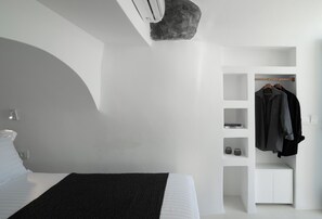 A modern bedroom with a bed, a built-in wardrobe, and a small seating area.