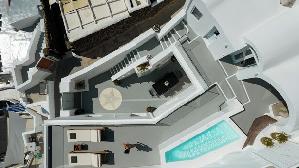 A modern building with a swimming pool, a sun terrace, and a dining area. - ORANA Residence Santorini (Thira - Santorini)