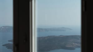 Une vue sur la côte, aperçue à travers une fenêtre, avec un paysage rocheux et des eaux calmes.