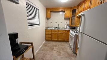 A compact kitchen with wooden cabinets, a built-in oven, and a coffee maker on a small table.