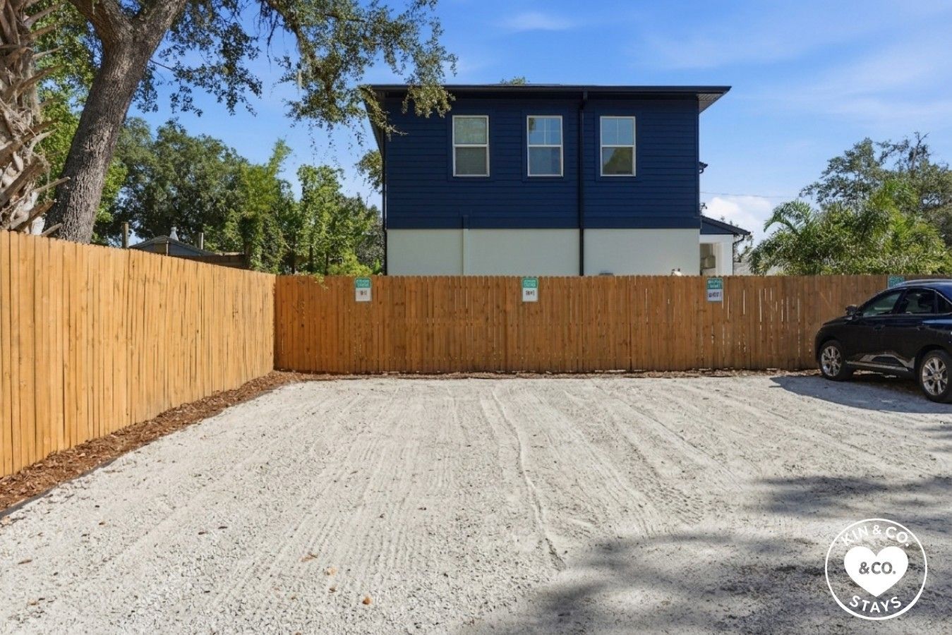A two-story building with a blue exterior and a fenced backyard.