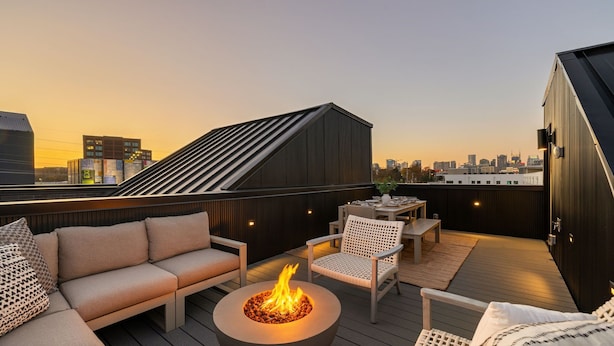 Eine Dachterrasse mit Feuerstelle, Sitzbereich und Blick auf die Stadtlandschaft.