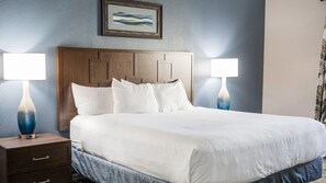 Ein Hotelzimmer mit einem großen Bett, zwei Nachttischen mit Lampen, einem Holzkopfstück und einem gerahmten Bild an der Wand.