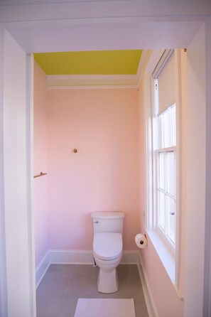 Ein kleines Badezimmer mit Toilette, Toilettenpapier und einem Fenster.