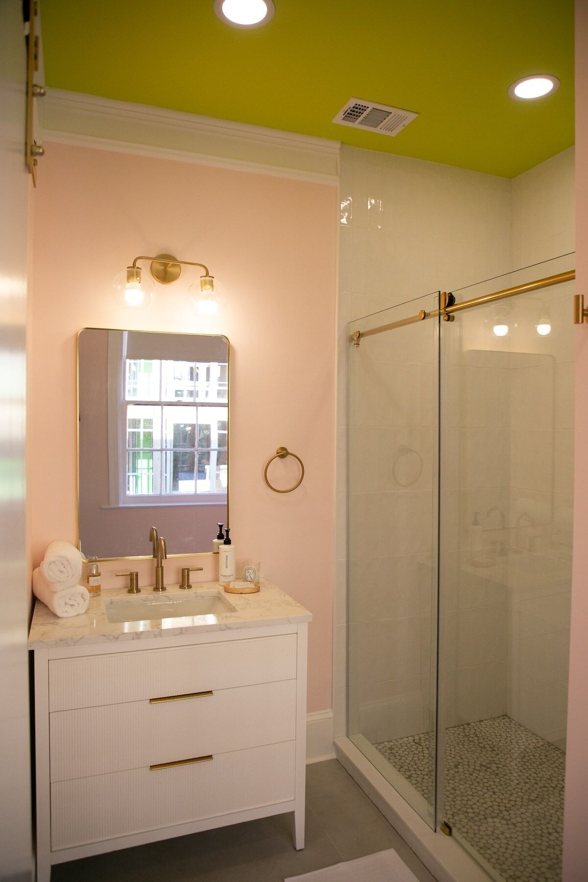 Une salle de bain avec un meuble-lavabo blanc, un miroir et une cabine de douche en verre.