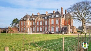 A large, historic building with multiple windows and a prominent tower. - Gîtes de France® Le cottage du parc (ROCQUEFORT)