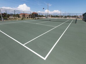 A tennis court with a net, surrounded by a fence and houses in the background. - Surf Dweller 712 - Wave Whisperer (Fort Walton Beach)