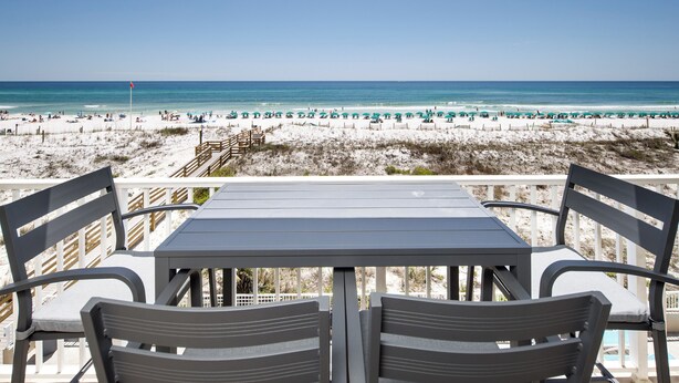 A beachside table with chairs overlooking a sandy beach and ocean. - Gulf Dunes 304- Saltwater Solace (Fort Walton Beach)