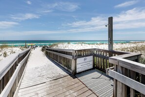 A wooden boardwalk leading to a beach with a sign warning against leaving items on the beach. - Gulf Dunes 210 - Coastal Charm (Fort Walton Beach)