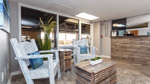 A modern interior with rustic wooden chairs, a coffee table, and a reception desk. - Gulf Dunes 210 - Coastal Charm (Fort Walton Beach)