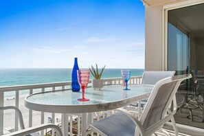 A balcony with a glass table, two chairs, and a potted plant. - Island Princess 605 - Coastal reflections (Fort Walton Beach)