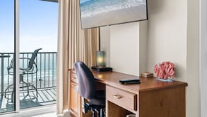 Une chambre d’hôtel équipée d’un bureau, d’une chaise et d’une grande fenêtre donnant sur la plage.