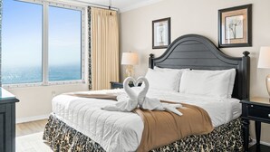 Une chambre d’hôtel avec un lit, un ventilateur de plafond, une fenêtre avec des rideaux et des œuvres d’art encadrées accrochées au mur.