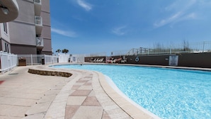 Une piscine avec une terrasse carrelée, une clôture blanche et un panneau indiquant qu’il est interdit de plonger.