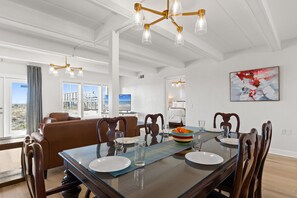 A dining area with a glass table, wooden chairs, and a chandelier. - Coconut Beach House B (Fort Walton Beach)