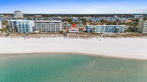 A beachfront hotel with multiple buildings, a sandy beach, and clear waters. - Coconut Beach House A (Fort Walton Beach)