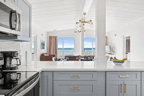 A modern kitchen with a large island, stainless steel appliances, and a view to the outside. - Coconut Beach House A (Fort Walton Beach)