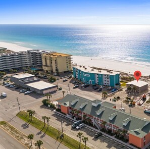 A coastal hotel with a beach view, multiple parking lots, and a prominent building with a blue facade. - Coconut Beach House A (Fort Walton Beach)