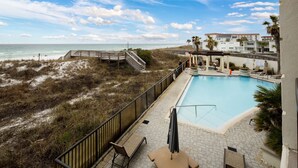 A pool area with a view of the beach and ocean, a wooden deck, and lounge chairs. - Bella Riva 108 - Golden Horizon (Fort Walton Beach)