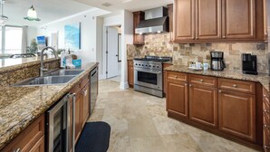 A modern kitchen with granite countertops, stainless steel appliances, and wooden cabinets. - Bella Riva 108 - Golden Horizon (Fort Walton Beach)