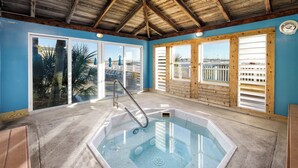 A hot tub in a room with large windows, a wooden ceiling, and a concrete floor. - Sea Oats 704 - Coral Shores (Fort Walton Beach)