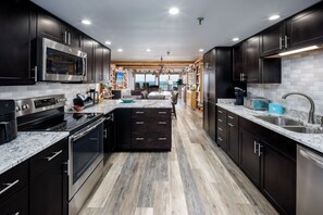 Una cucina moderna con mobili scuri, elettrodomestici in acciaio inossidabile e un piano di lavoro in marmo.